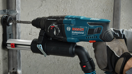 Máy khoan Bosch Professional màu xanh lam đang hoạt động trên tường.