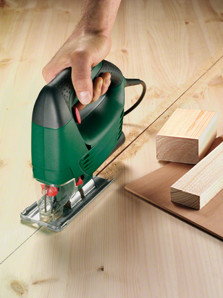 Một công nhân đang điều khiển máy cưa lọng cắt ván ép theo đường đã đánh dấu.