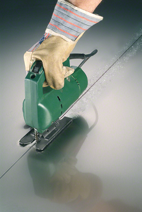 Người đeo thiết bị an toàn sử dụng máy cưa lọng để cắt một đường thẳng trên kim loại.