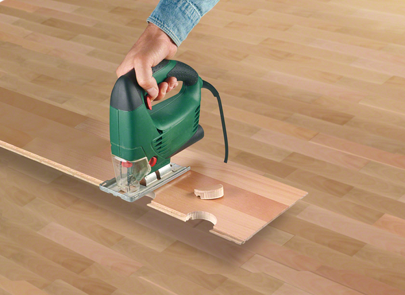 Một người sử dụng máy cưa lọng để cắt một khía tròn trên tấm ván gỗ.