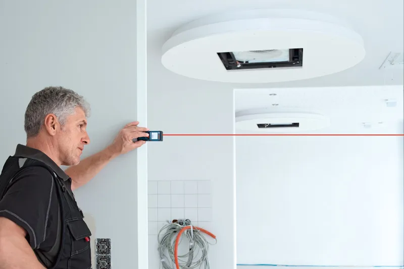 GLM 40-12 Một người sử dụng máy đo laser để đo khoảng cách tại một công trường xây dựng trong nhà.