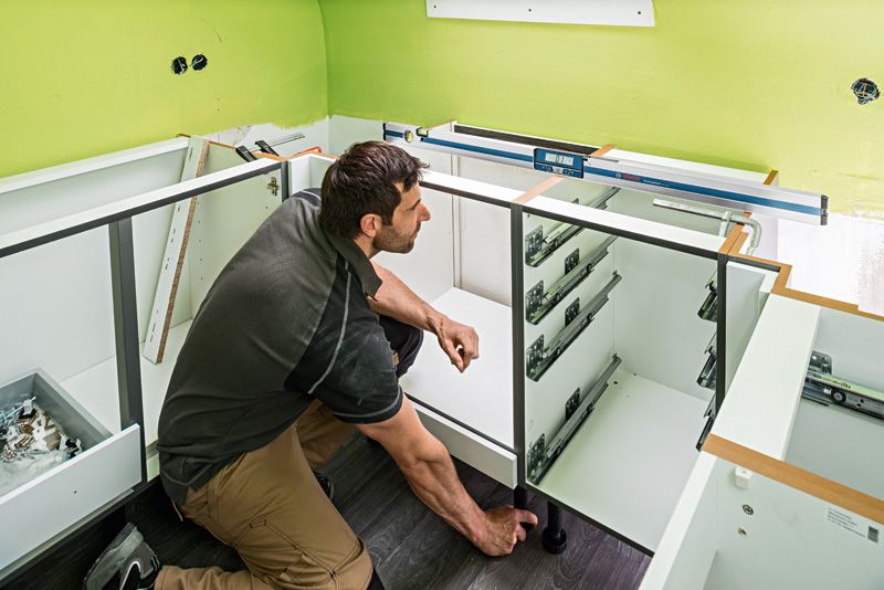 GIM 120 Một người đang lắp tủ trong khi sử dụng máy đo độ nghiêng kỹ thuật số trên quầy.