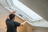 Người đang đo góc cửa sổ bằng máy đo độ nghiêng kỹ thuật số trong một căn phòng gác mái đã hoàn thiện.