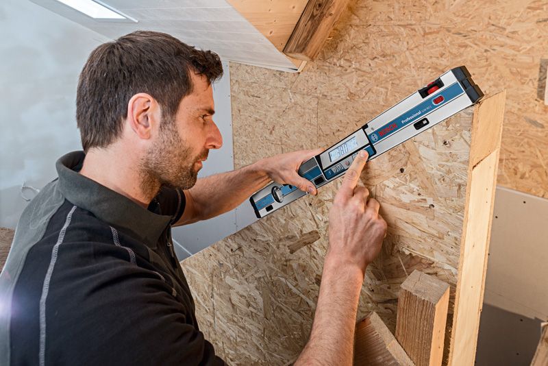 Người đang đo bề mặt gỗ góc cạnh bằng máy đo độ nghiêng kỹ thuật số.