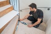 Một người đo góc cầu thang bằng thước đo góc gắn trên cầu thang.