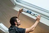 Người đang cầm máy đo độ nghiêng kỹ thuật số để đo góc của trần nhà dốc.