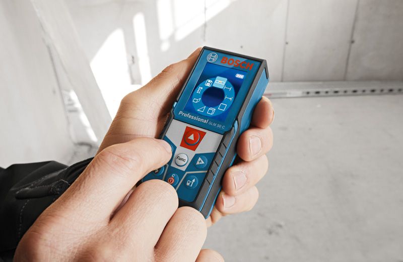 Người vận hành máy đo laser kỹ thuật số trong một căn phòng chưa hoàn thiện.