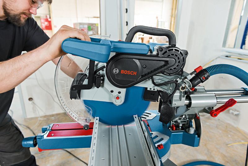 GCM 12 SDE Một người mặc đồ bảo hộ đang vận hành máy cưa góc trượt để cắt gỗ chính xác.
