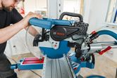 Một người mặc đồ bảo hộ đang vận hành máy cưa góc trượt để cắt gỗ chính xác.
