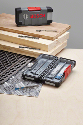 Bộ lưỡi cưa ghép hình được trưng bày trên tấm gỗ và kim loại, các lưỡi cưa được sắp xếp gọn gàng trong hộp đựng.