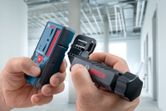 Một người đang lắp ráp máy đo laser và giá đỡ trong một tòa nhà đang xây dựng.
