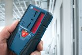 Người đang cầm máy thu tia laser trong một tòa nhà đang được xây dựng.