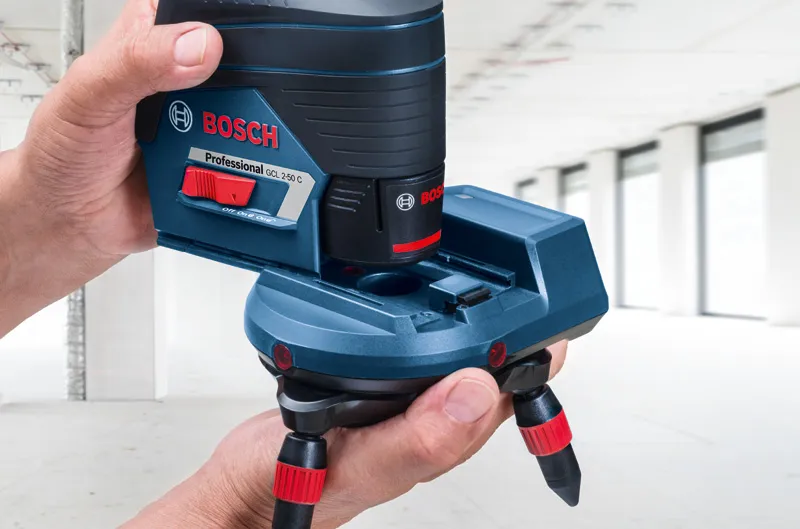 RM 3 Một người đang điều chỉnh phụ kiện của dụng cụ cân bằng laser trong một căn phòng sáng sủa và chưa hoàn thiện.