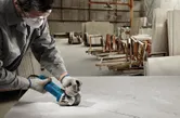 Một người mặc đồ bảo hộ đang cắt một phiến đá cẩm thạch lớn bằng một dụng cụ điện.