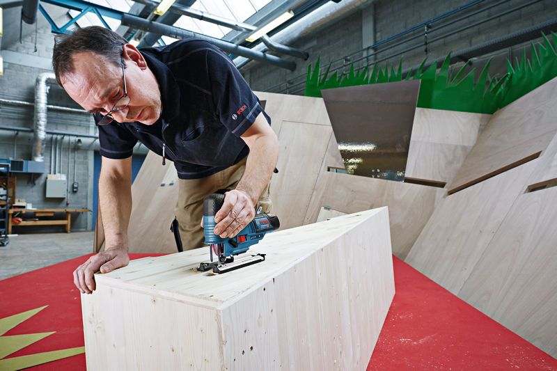 Một người sử dụng máy cưa lọng không dây để cắt gỗ trong xưởng.