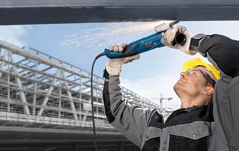 Một người mặc thiết bị an toàn mài kim loại trên cao, tạo ra tia lửa.