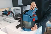 Một người lắp pin vào máy hút bụi không dây trên bàn làm việc.
