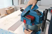 Một người đang lắp pin vào máy hút bụi không dây trên bàn làm việc.
