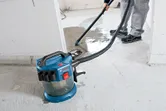Một người sử dụng máy hút bụi không dây để làm sạch chất lỏng trên sàn bê tông.