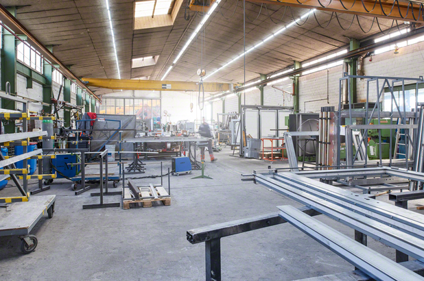 Object #200255835: SennAG22908_cmyk Công nhân mặc đồ bảo hộ di chuyển qua xưởng chế tạo kim loại.