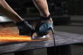 Một người mặc đồ bảo hộ sẽ mài kim loại, tạo ra tia lửa sáng.