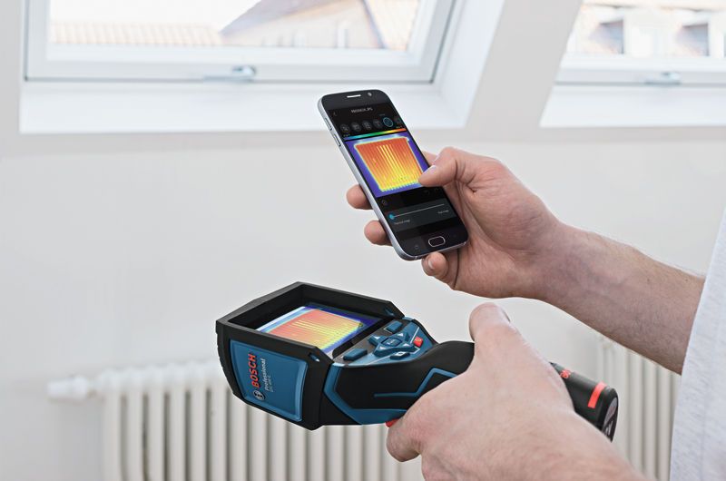 Một người sử dụng camera nhiệt và điện thoại thông minh để xem hình ảnh nhiệt trong nhà.