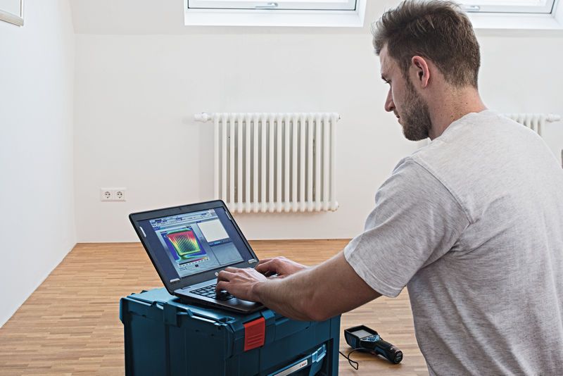 Người đang phân tích dữ liệu camera nhiệt trên máy tính xách tay trong phòng có bộ tản nhiệt.