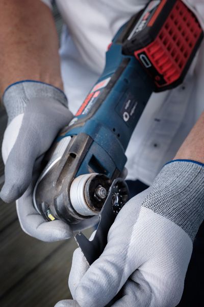 Một người đeo thiết bị an toàn gắn lưỡi cắt vào dụng cụ điện không dây.
