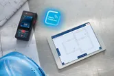 Đo bằng tia laser trên bản thiết kế bên cạnh máy tính bảng kỹ thuật số hiển thị kế hoạch xây dựng.