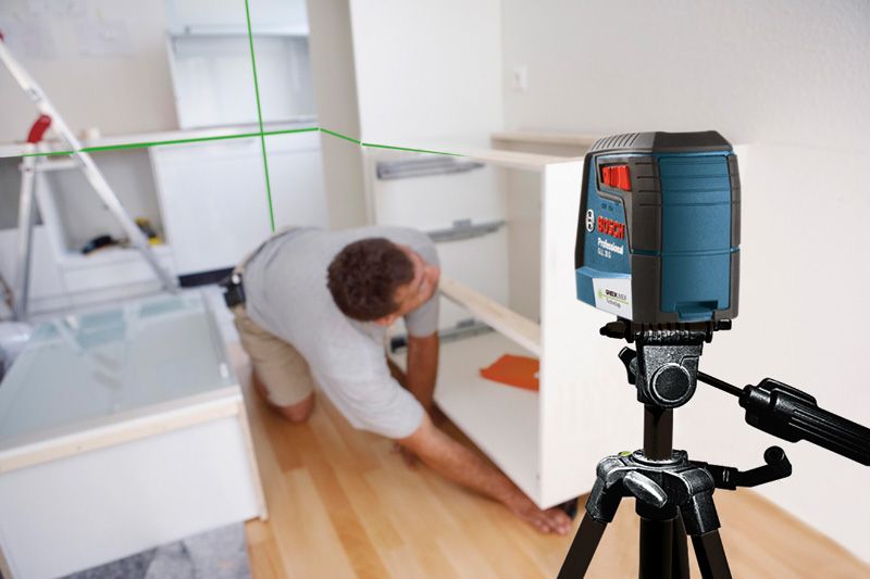 GLL 30 G Một người đang lắp tủ trong bếp bằng cách sử dụng máy cân bằng laser trên giá ba chân.