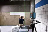 Người ta lắp gạch ốp tường bằng dụng cụ cân bằng laser để căn chỉnh các hàng.