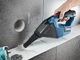 Người ta sử dụng máy hút bụi không dây để hút bụi trên bề mặt gạch lát.