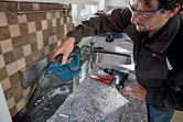 Người mặc đồ bảo hộ đang dọn dẹp mảnh vụn xây dựng bằng máy hút bụi không dây.