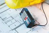 Máy đo laser, bản vẽ kỹ thuật, mũ bảo hiểm.