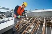 Một người mặc đồ bảo hộ đang cắt thép cây bằng máy cắt điện tại công trường xây dựng.