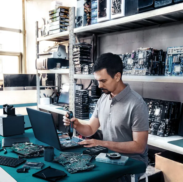 Bosch GO Một người sử dụng tua vít không dây để lắp ráp các linh kiện điện tử tại bàn làm việc.