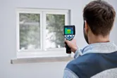 Người sử dụng camera nhiệt để kiểm tra cửa sổ từ bên ngoài tòa nhà.