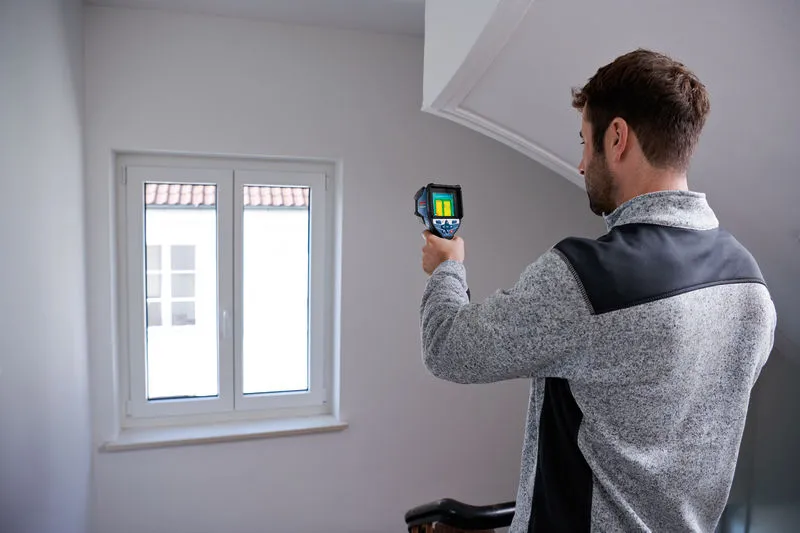 GTC 600 C Một người đang quét khu vực cửa sổ bằng camera nhiệt bên trong tòa nhà.