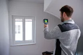 Một người đang quét khu vực cửa sổ bằng camera nhiệt bên trong tòa nhà.