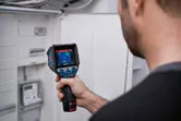 Một người sử dụng camera nhiệt để kiểm tra bảng điện.