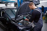 Một người mặc đồ bảo hộ đang kiểm tra động cơ ô tô bằng camera nhiệt.