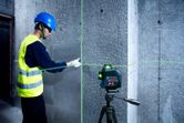 Một người mặc thiết bị an toàn đang căn chỉnh gạch trên tường bằng dụng cụ cân bằng laser.