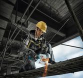 Một người mặc đồ bảo hộ đang sử dụng máy mài góc để cắt giàn giáo kim loại.