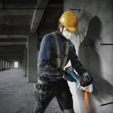 Một người mặc đồ bảo hộ đang cắt bê tông bằng máy mài góc.