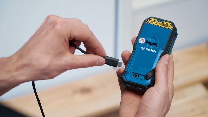 Một người đang kết nối cáp sạc vào mặt sau của dụng cụ điện cầm tay.