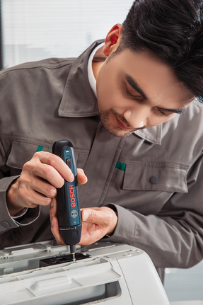 Một người đang lắp ráp máy văn phòng bằng tua vít không dây.