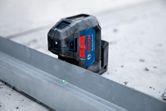 Máy cân bằng laser chiếu các điểm màu xanh lá cây lên đường ray kim loại trên sàn bê tông.
