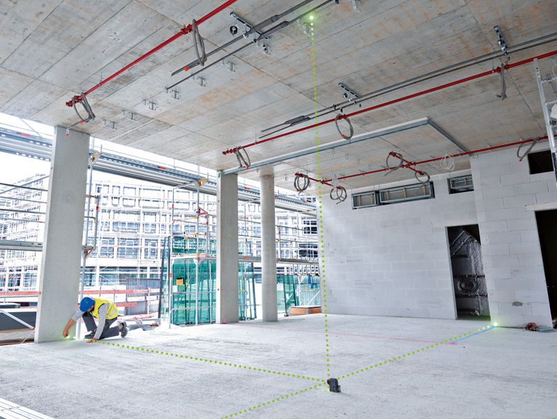 Người đeo thiết bị an toàn sử dụng máy cân bằng laser để căn chỉnh các điểm trong khu vực xây dựng.