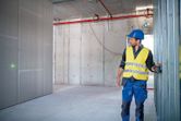 Một người mặc thiết bị an toàn đang sử dụng máy cân bằng laser để căn chỉnh khung tường.
