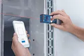 Một người sử dụng máy đo laser để ghi lại dữ liệu khoảng cách trên điện thoại thông minh.